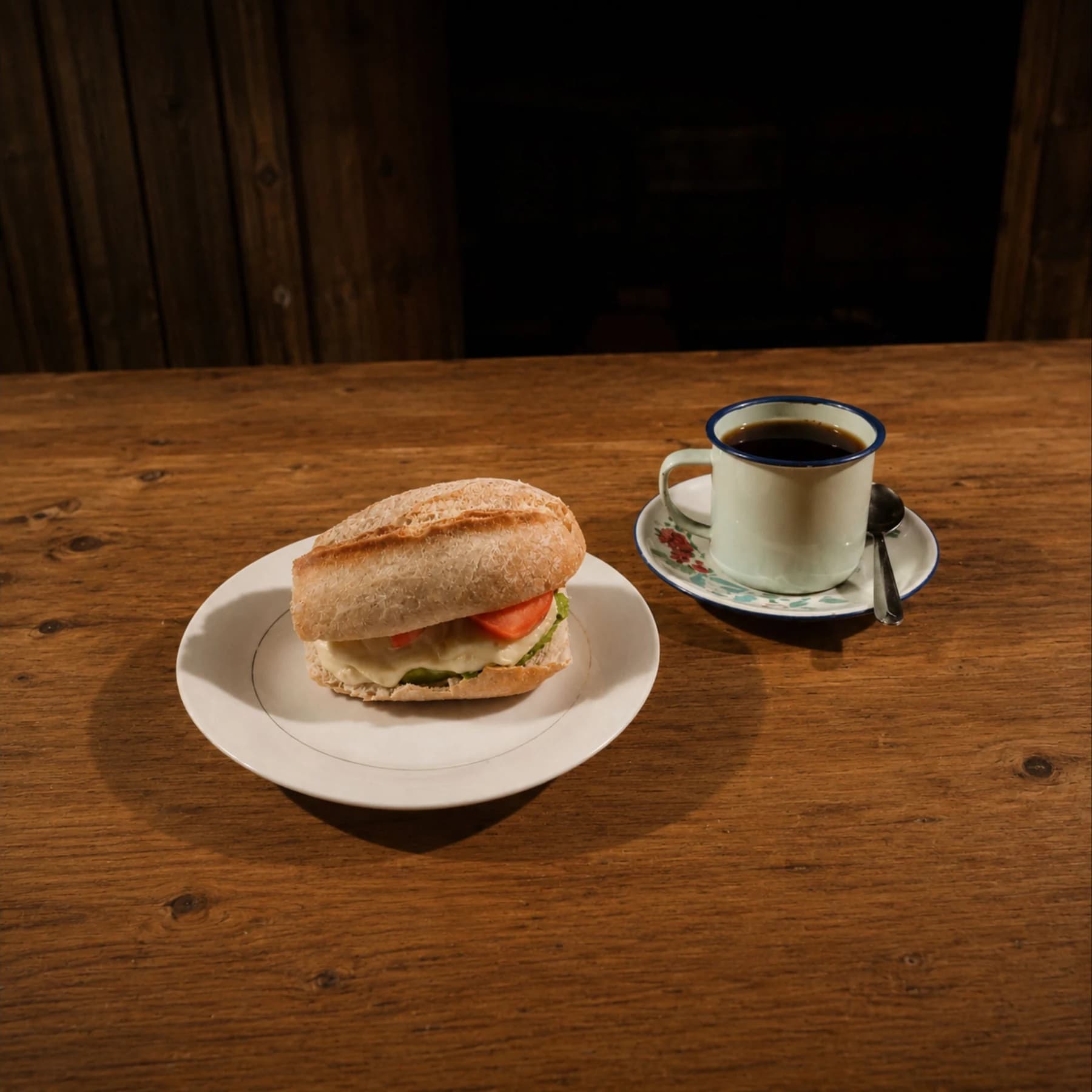 Café tradicional paceño acompañado de un sándwich de palta sobre una mesa de madera